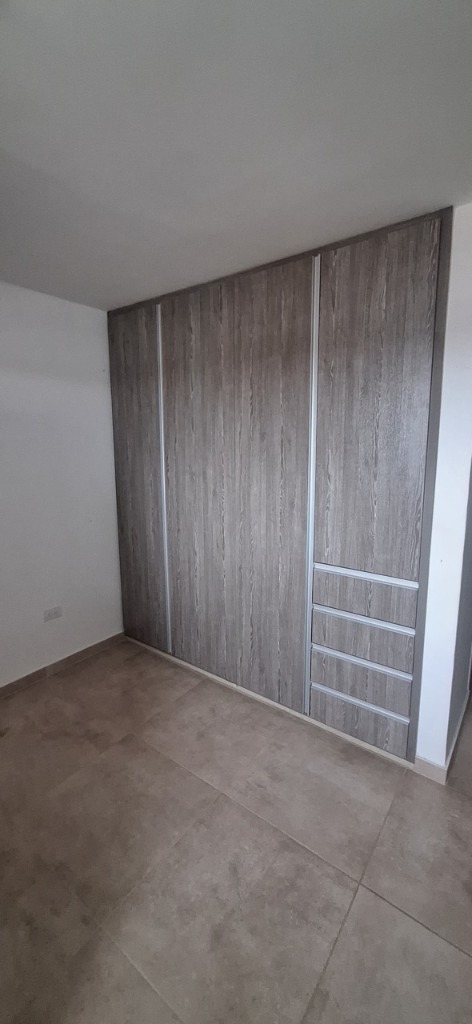 Closet de piso a techo en MDF texturado gris con cajoneras integradas y manijas de aluminio