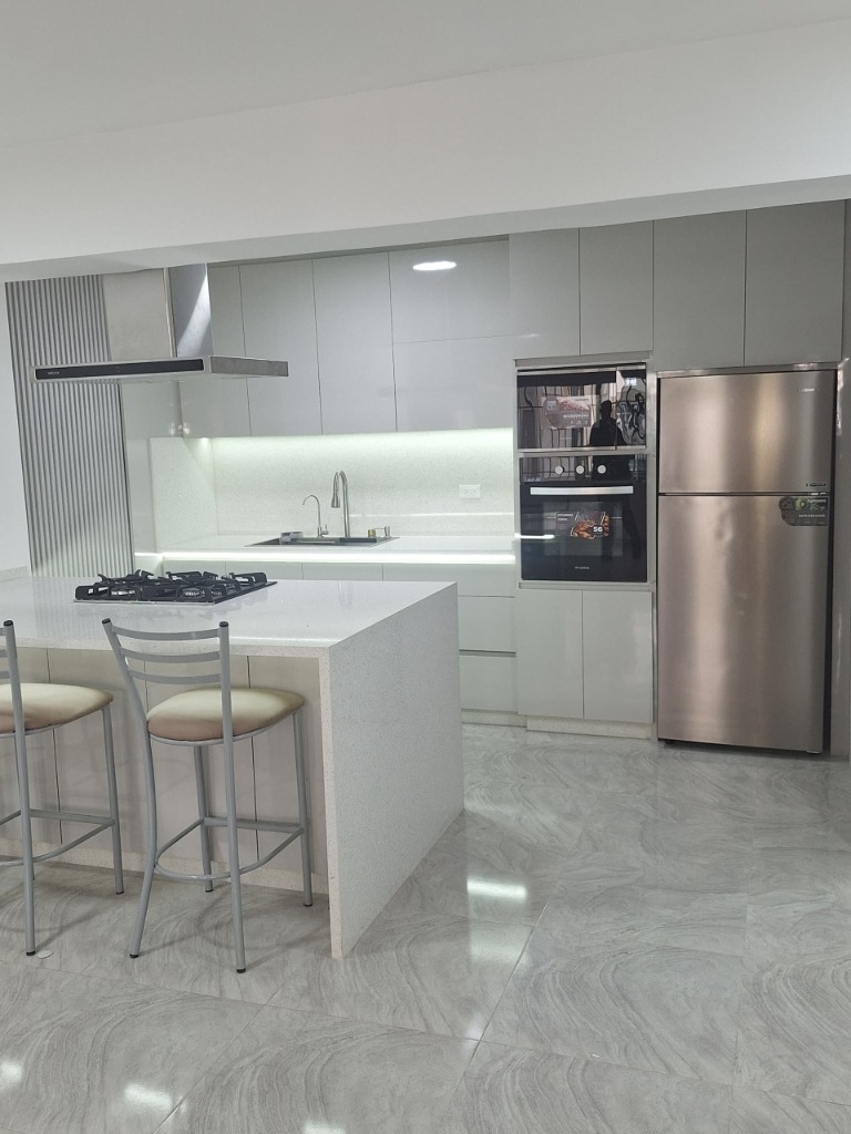 Cocina en L con barra desayunadora de cuarzo y torre de hornos integrada