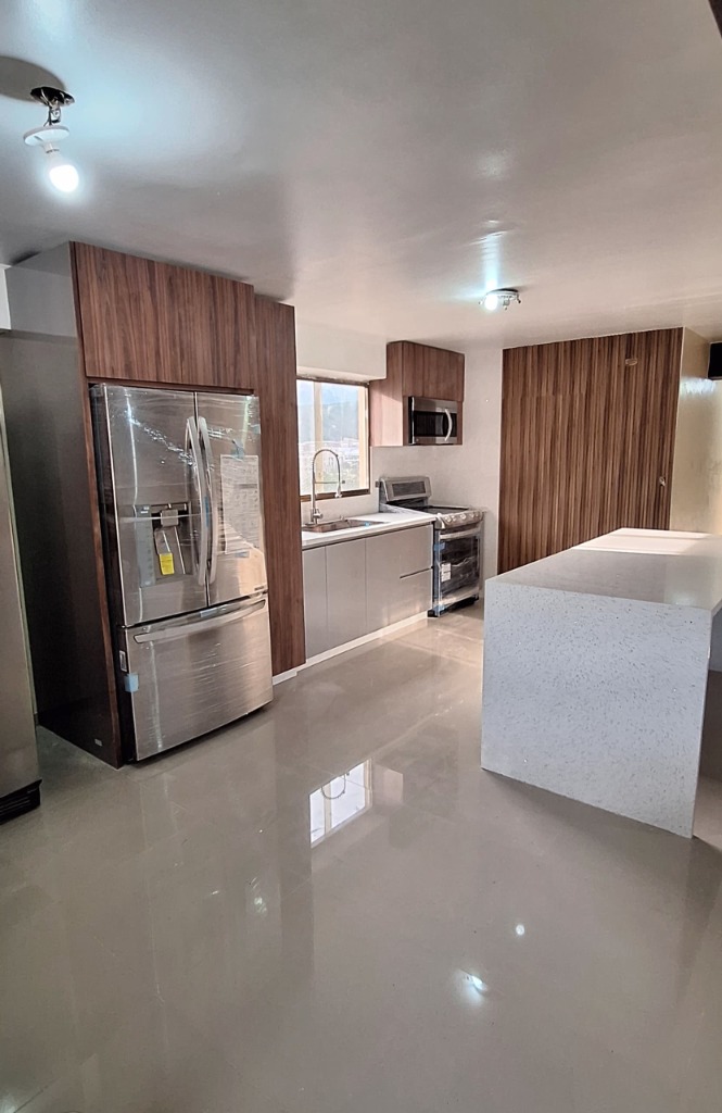 Cocina integral en acabado madera natural con isla de cuarzo blanco